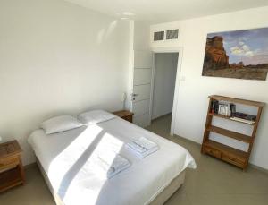 een slaapkamer met een bed met witte lakens en een schilderij bij Sunny 3BR Apartment Golf Residence in Eilat +24 foto's