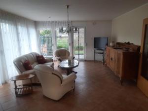 a living room with couches and a table and a tv at Ferienhaus am Kulkwitzer See in Leipzig