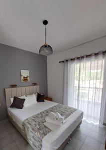a bedroom with a large bed and a large window at House Stella Kalamitsi - Studios & Apartments in Kalamitsi