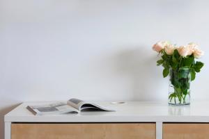 a vase of pink roses and a book on a table at Elite Apartments Seaview Tower in Gdańsk