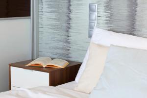 a bed with a book on a night stand next to a window at Elite Apartments Seaview Tower in Gdańsk