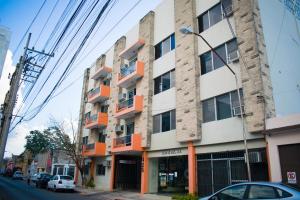 an apartment building with orange balconies on a city street at Suites del Sol Hotel & Apartments in Mérida