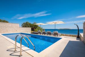 uma piscina com cadeiras e guarda-sóis em Villa Carisma island Vis em Vis