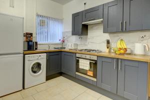 cocina con armarios grises, lavadora y secadora en Modern 2BR Gem I Free Parking I Sleeps 5, en Coventry