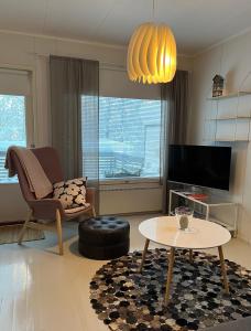 - un salon avec une chaise, une table et une télévision dans l'établissement Saunallinen huoneisto Kolilla, à Kolinkylä