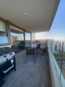 sala de estar con mesa y sillas en el balcón en departamento con vista al mar, en Concón