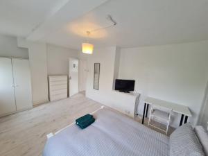 a white room with a bed and a tv at London E2 Rooms in London