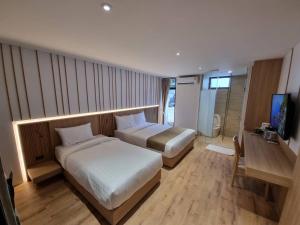 Habitación de hotel con 2 camas y TV en Nirundorn Resort Chaam, en Cha Am
