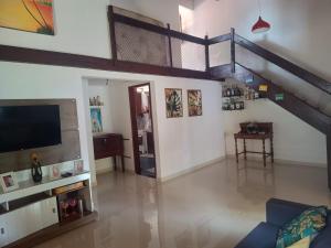 uma sala de estar com televisão e uma escadaria em Casa da Mari em Vera Cruz de Itaparica