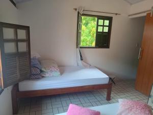 um pequeno quarto com uma cama e uma janela em Casa da Mari em Vera Cruz de Itaparica