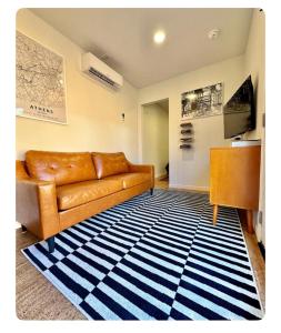 a living room with a brown couch and a blue and white rug at Nomehaus shipping container studio residential neighborhood ATHENS in Athens