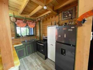 Il comprend une cuisine équipée d'un réfrigérateur et d'une cuisinière. dans l'établissement Parque Nacional Volcán Poás Cabaña Abby, à Bajos Tigre