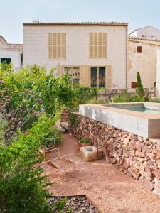 een achtertuin met een stenen muur en een zwembad bij Ses Sucreres Small & Slow Hotel in Ferreries