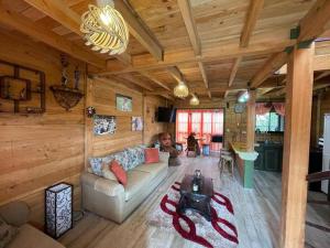 un homme assis sur un canapé dans un salon dans l'établissement Parque Nacional Volcán Poás Cabaña Abby, à Bajos Tigre