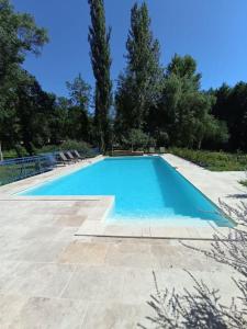 una gran piscina azul con sillas y árboles en Domaine de La Barde guest rooms and suites., en Le Bugue