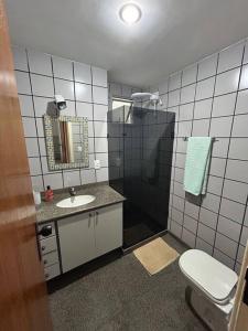 ein Bad mit einem Waschbecken und einer Dusche mit einem WC in der Unterkunft Apartamento de 3 quartos na Praia da Fonte Guarapari in Guarapari