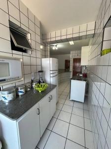 eine Küche mit weißen Geräten und einer schwarzen Arbeitsplatte in der Unterkunft Apartamento de 3 quartos na Praia da Fonte Guarapari in Guarapari