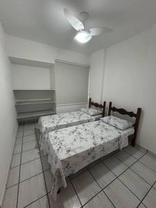two beds in a bedroom with a ceiling fan at Apartamento de 3 quartos na Praia da Fonte Guarapari in Guarapari