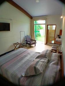 a bedroom with a large bed and a chair at Green Lodge Eco Life Hotel in Florianópolis