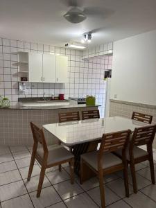 a kitchen with a table and chairs and a kitchen with white cabinets at Apartamento de 3 quartos na Praia da Fonte Guarapari in Guarapari