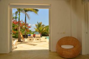 an open door to a patio with palm trees and a chair at Villa Los Cocos Baru in Barú