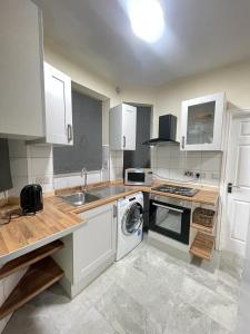 a kitchen with white cabinets and a washing machine at Airstaybnb in Manchester