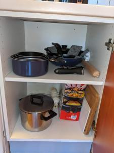 uma prateleira de cozinha com panelas, frigideiras e outros artigos em Horizon Pelvoux Accueillant T2 pied des pistes em Puy-Saint-Vincent