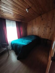 a bed in a wooden room with a window at Grandes cabañas in Pucón