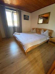 a bedroom with a large bed with a wooden floor at Casa Nicolae in Silvaşu de Sus