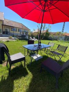 a table and two chairs and a red umbrella at Casa Nicolae in Silvaşu de Sus