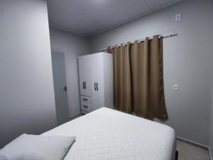 niewielka sypialnia z łóżkiem i zasłoną w obiekcie Casa nas termas de Piratuba w mieście Piratuba