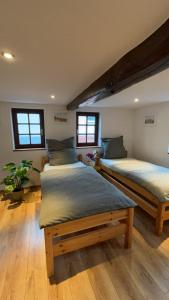 twee bedden in een kamer met houten vloeren en ramen bij Fachwerkhaus zum Hirsch in Mömbris