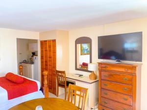 a bedroom with a bed and a desk with a television at Point Salines Hotel in Gwa Kay