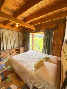 a large bed in a room with a window at Hostal El Durmiente a 5 minutos del centro de Panguipulli in Panguipulli