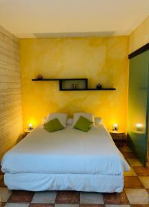 a bedroom with a white bed with a yellow wall at L'étape Provencale in Cabriès