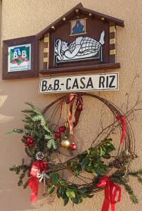 a christmas wreath with a sign on a wall at B&B Casa Riz in Castello di Fiemme