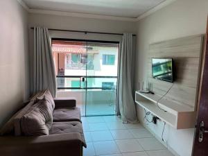 sala de estar con sofá y puerta corredera de cristal en Apartamento mobiliado en Porto Seguro