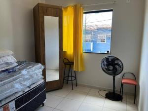 um quarto com uma cama, uma janela e uma ventoinha em Apartamento mobiliado em Porto Seguro