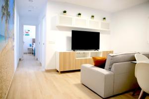 sala de estar con sofá y TV en Suites Verano Azul en Castillo del Romeral