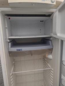un refrigerador vacío con la puerta abierta y su arte cambiando en Descanse e aconchego, en Itajaí