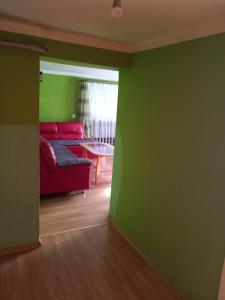 a living room with a red couch and a green wall at Apartamenty pod Rykowiskiem in Korbielów