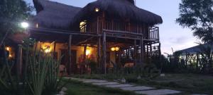 a house with a thatched roof with a pathway at Arcoiris Casahostal in San Bernardo del Viento