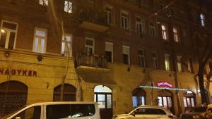 twee auto's geparkeerd voor een gebouw 's nachts bij Nefelejcs apartman (Netflix) in Boedapest
