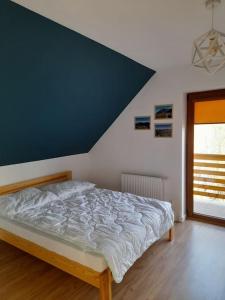 a bed in a bedroom with a blue wall at Dom pod Leskowcem in Ponikiew
