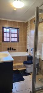 a bathroom with a tub and a toilet and a sink at Jo's Eden in Edenvale