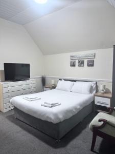 a bedroom with a large white bed and a tv at Poachers Pocket Seaview in Bacton