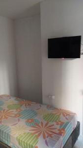 um quarto com uma cama e uma televisão na parede em LA MEDELLIN HOSTAL em Cartagena das Índias