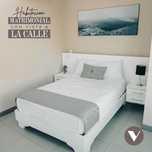 a white bed in a white bedroom with aigil calle sign at Hotel Viera Chimbote in Chimbote