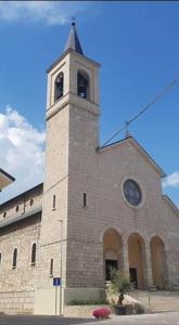 een kerk met een toren met een klok erop bij Casa vacanza La Genziana in Roccaraso