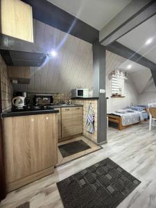 a kitchen with wooden cabinets and a bed in a room at Apartamenty u Grażyny in Kluszkowce
